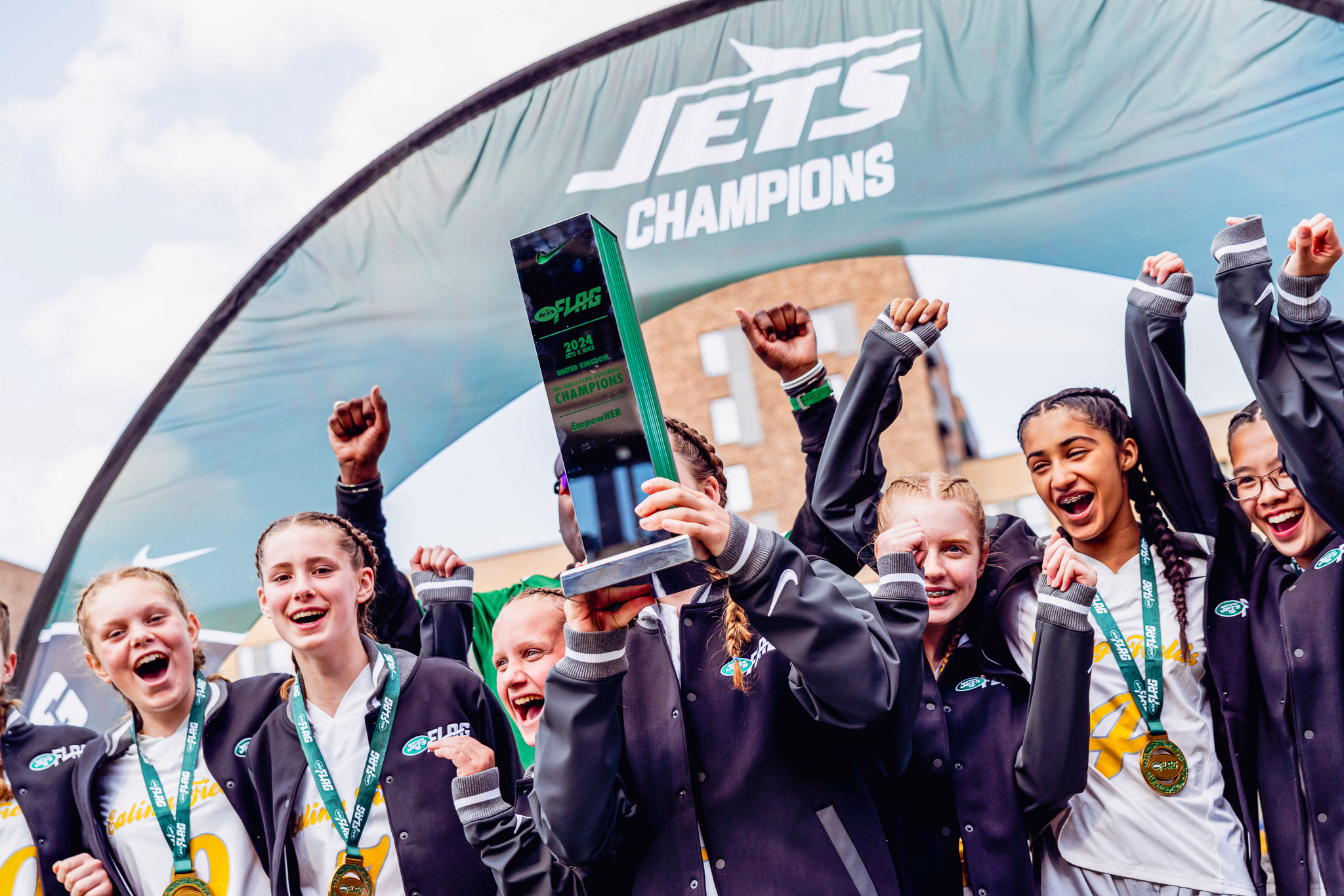 Jets NFL Girls Flag League winners posed with their trophy in London. 2024.